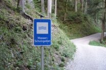 Ein Wasser-Schutzgebiet-Schild neben einem Waldweg.